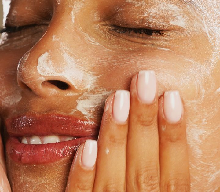 Model washing her face with a cleanser.